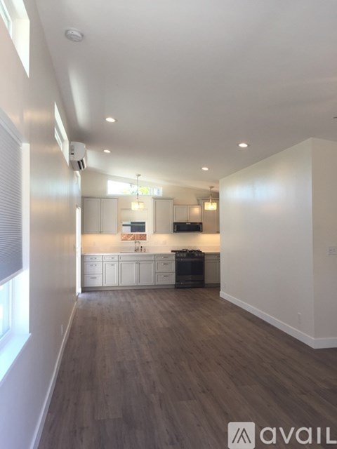 A modern kitchen with white cabinets and a wooden floor.
