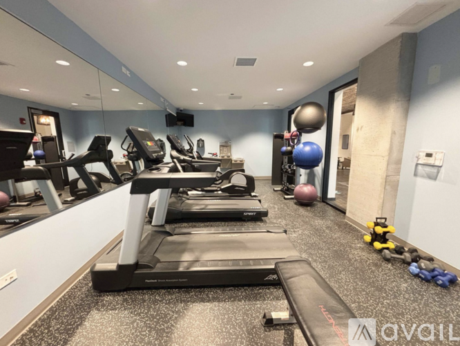 A gym with treadmills, exercise balls, and dumbbells.