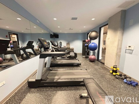 A gym with treadmills, exercise balls, and dumbbells.