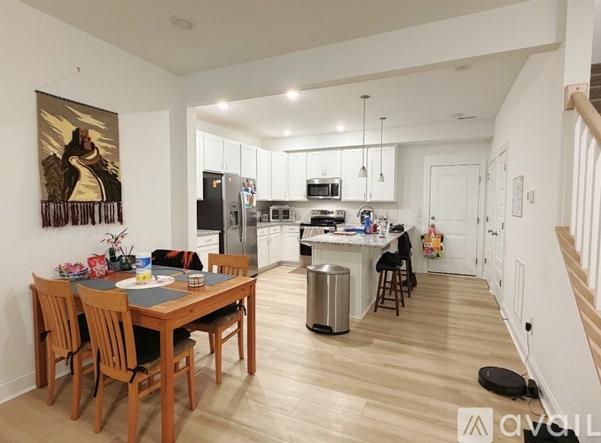 A kitchen with a dining table and chairs in the foreground and a painting hanging on the wall.