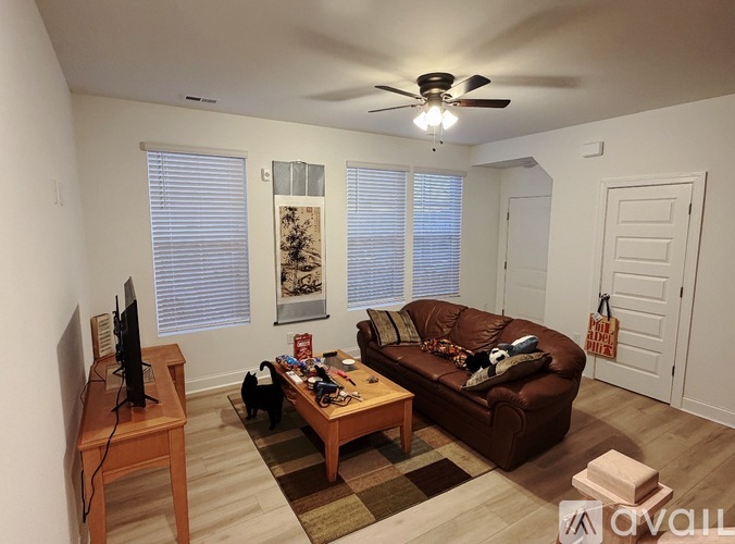 A living room with a brown couch, a wooden coffee table, and a television on a wooden stand.