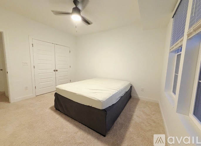A bedroom with a bed, a ceiling fan, and a closet.