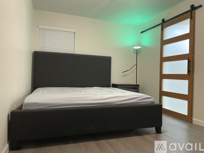 A bedroom with a black bed and a wooden door.