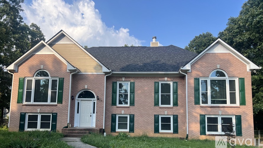 A two-story brick house with a white door and green shutters.