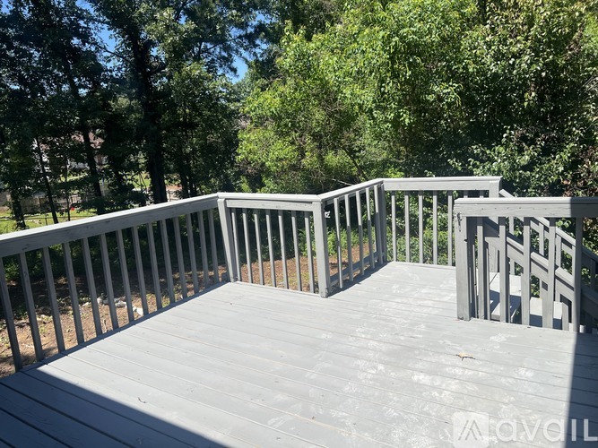 A wooden deck with railings and trees in the background.