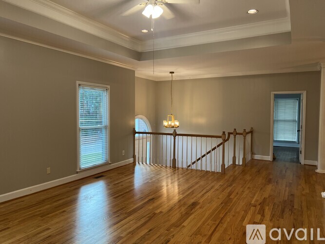 A spacious room with wooden floors and a staircase.