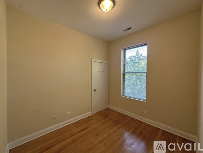 A room with wooden floors and a window showing trees outside.