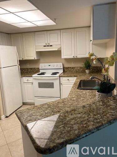 A kitchen with granite countertops and white appliances.