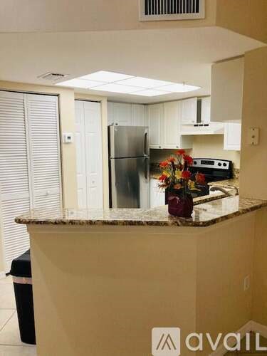 A kitchen with a granite counter top and a refrigerator.