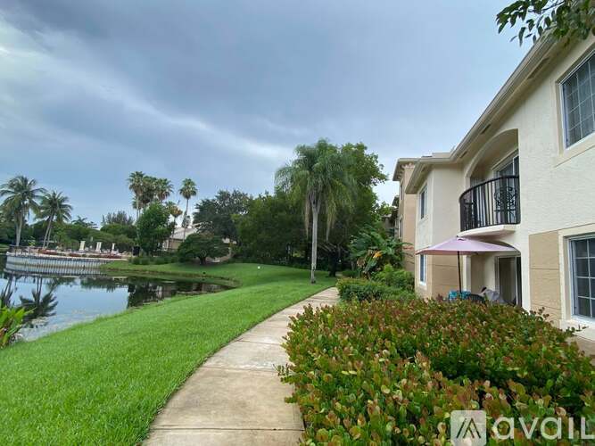 A house with a balcony is situated by a body of water with a walkway leading to it.
