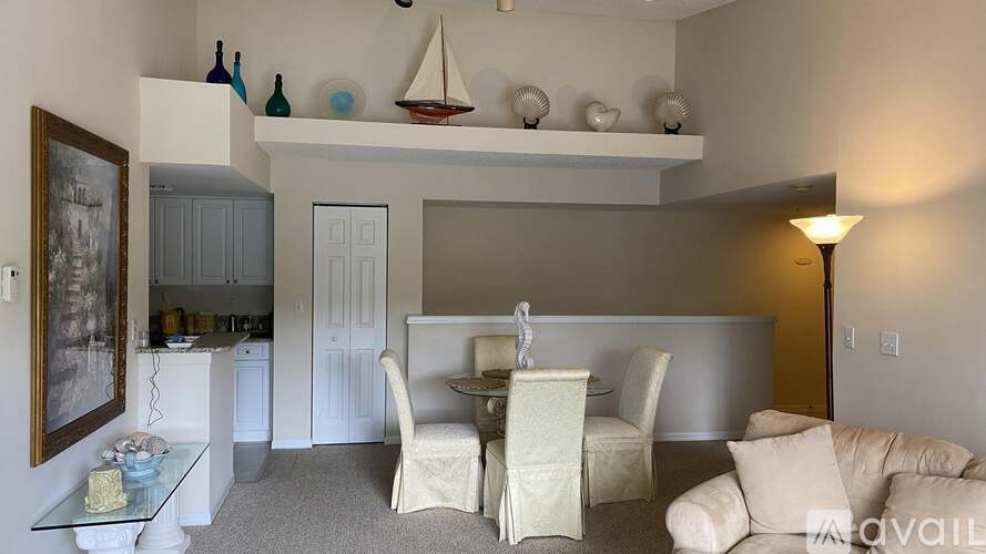 A living room with a white couch, a glass table, and a painting on the wall.