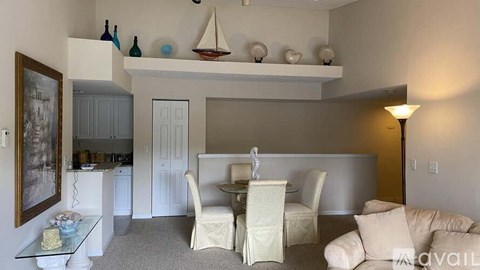 A living room with a white couch, a glass table, and a painting on the wall.