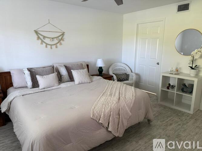 A bedroom with a bed, a chair, and a mirror.