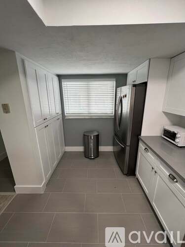 A kitchen with white cabinets and a black fridge.