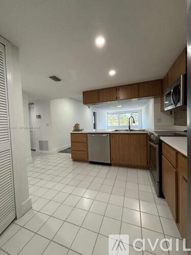 A kitchen with white tiled floors and wooden cabinets.