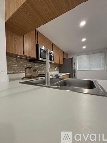 A modern kitchen with wooden cabinets and a stainless steel sink.