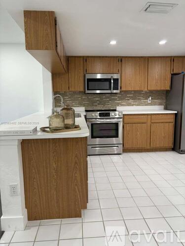 A kitchen with wooden cabinets and a white tile floor.