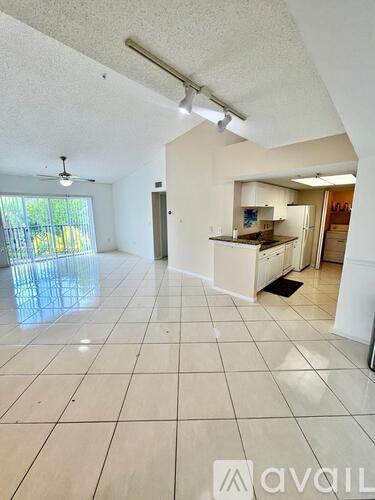 A spacious living room with a kitchen in the background.