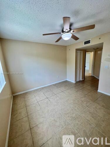 A room with a ceiling fan and tile flooring.