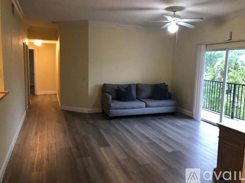 A living room with a grey couch and a ceiling fan.