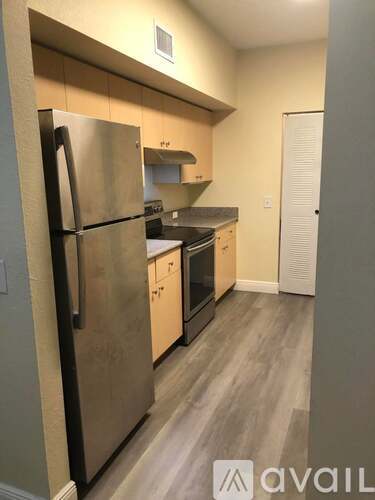 A kitchen with a refrigerator, cabinets, and a countertop.