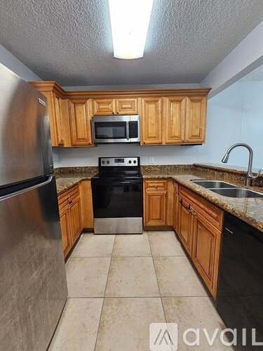 A kitchen with wooden cabinets and a stainless steel refrigerator.