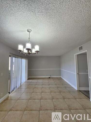 A room with a chandelier and tiled floor.