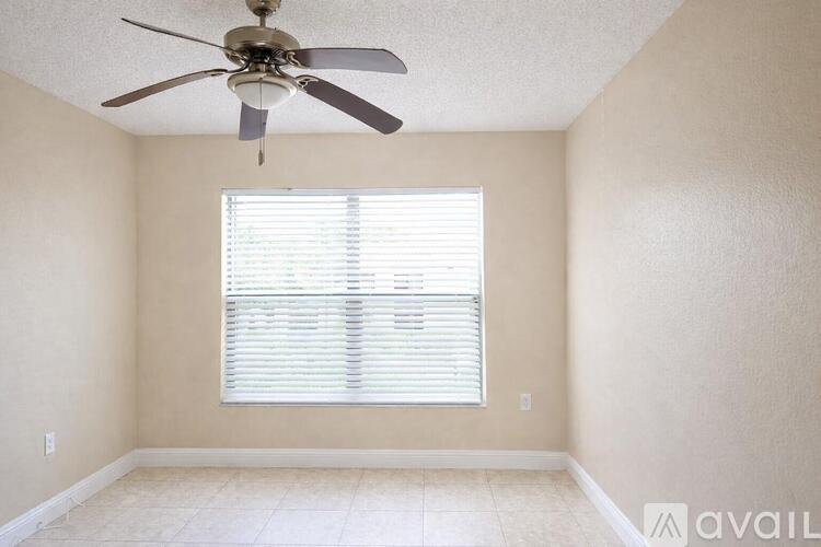 A room with a ceiling fan and a window with blinds.