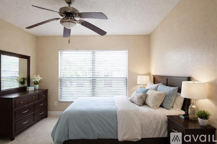 A bedroom with a bed, dresser, and ceiling fan.