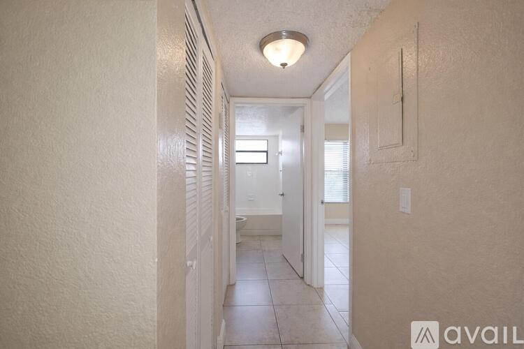 A long hallway with a light on the ceiling and a door at the end.