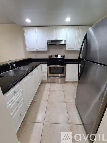 A kitchen with white cabinets and a stainless steel refrigerator.