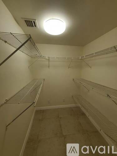 Empty walk-in closet with white shelves and a light on the ceiling.