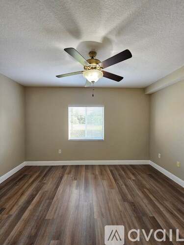 A room with a ceiling fan and wooden flooring.