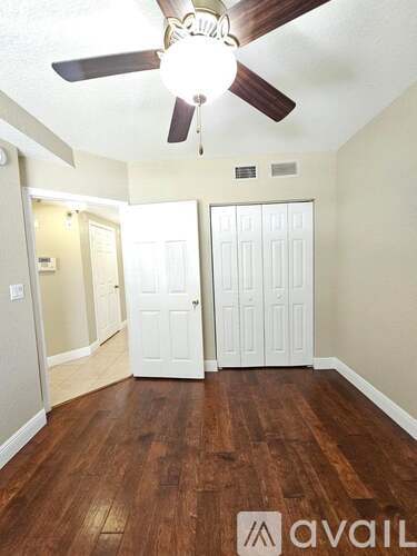 A room with a ceiling fan and wooden floors.