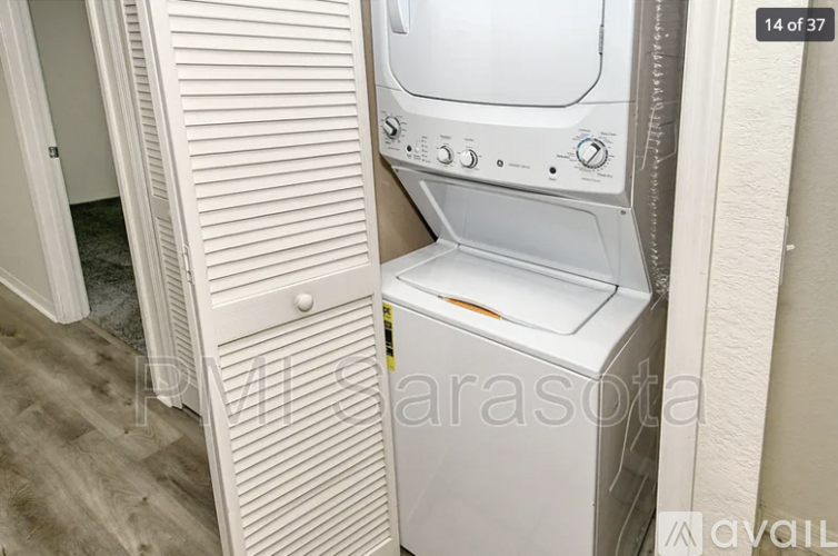 A white dryer is in a small space next to a white door.