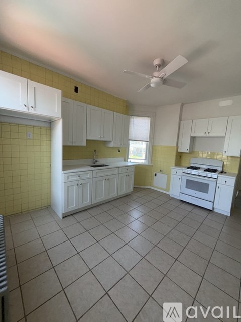 A kitchen with white cabinets and a fan on the ceiling.