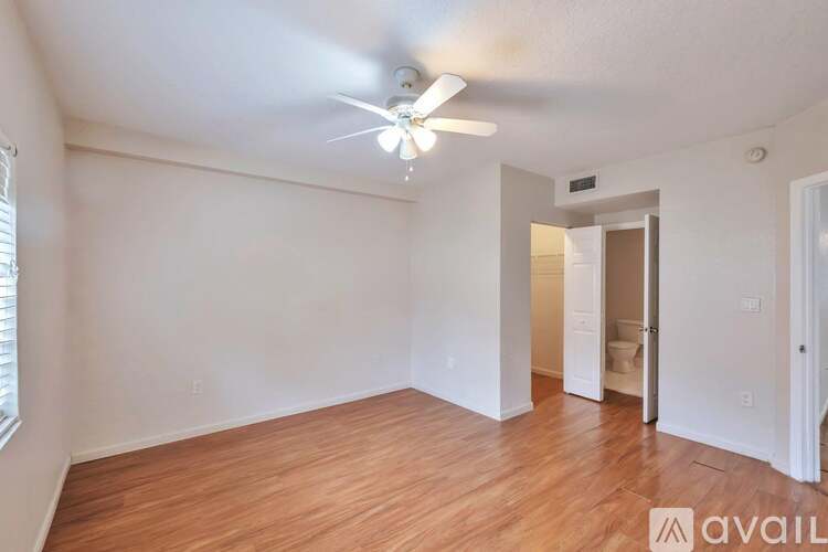 A room with a ceiling fan and wooden flooring.