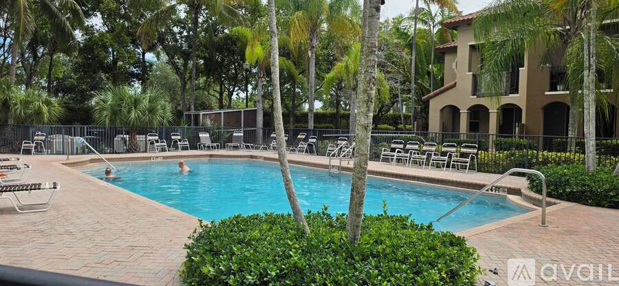 A pool surrounded by palm trees and lounge chairs.