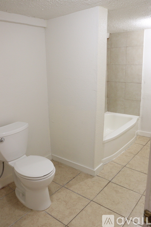 A white toilet in a bathroom with a white tub.