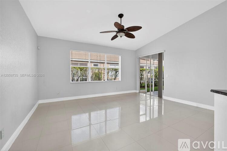 A spacious room with a ceiling fan and a large window.