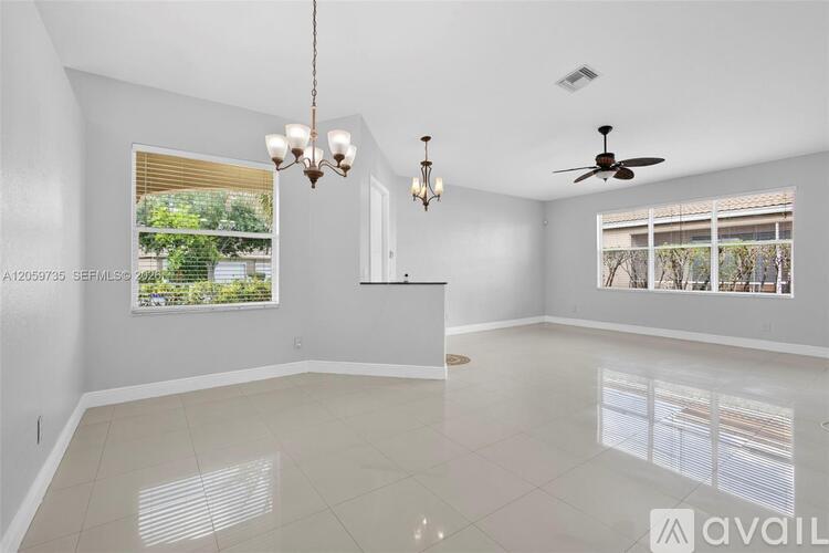 A spacious living room with a fan and a chandelier.