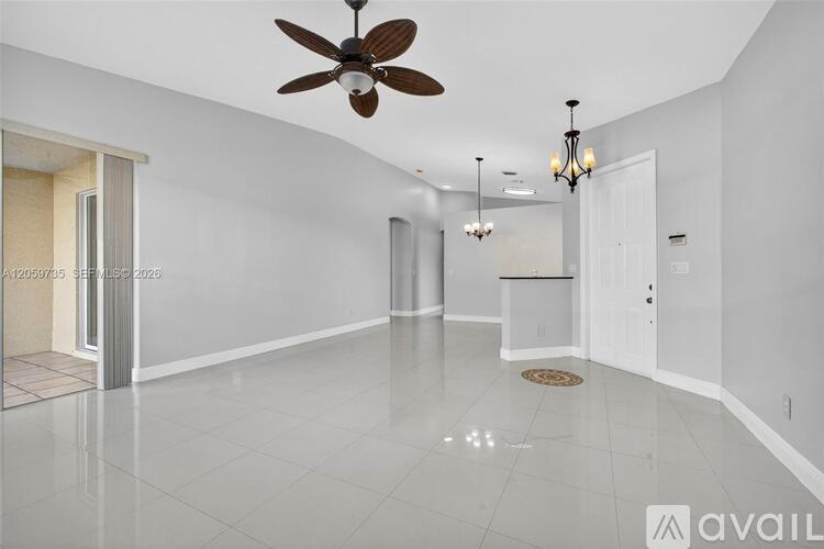 A spacious room with a ceiling fan and a chandelier.