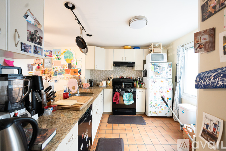 A kitchen with a refrigerator covered in magnets and a black stove top.