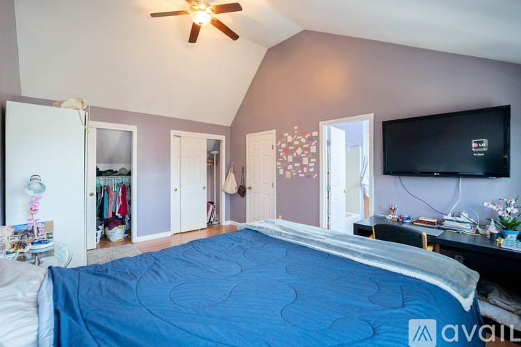 A bedroom with a blue bedspread and a ceiling fan.