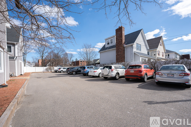 A parking lot with cars and houses in the background.