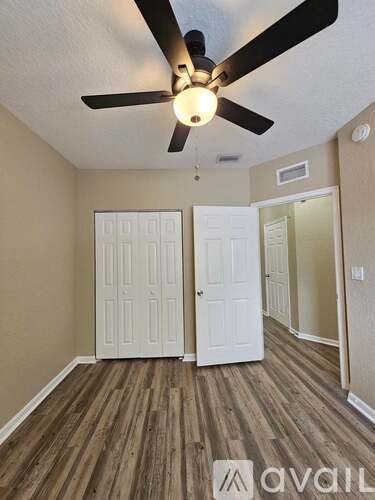 A room with a ceiling fan and two white doors.