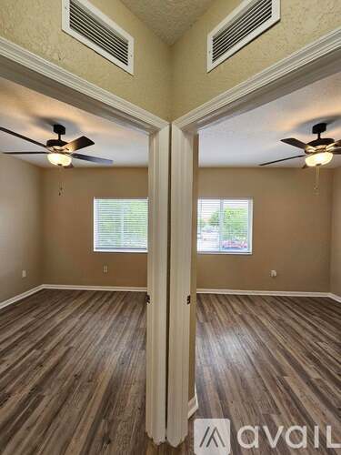 A room with wooden floors and two ceiling fans.