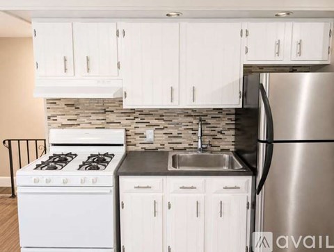 A kitchen with white cabinets and a stainless steel refrigerator.