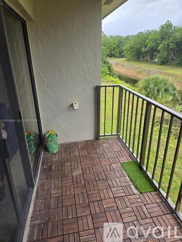A balcony with a brick floor and a metal railing overlooking a grassy area.