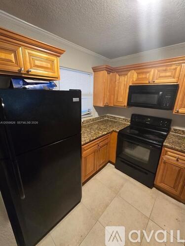 A kitchen with black appliances and wooden cabinets.